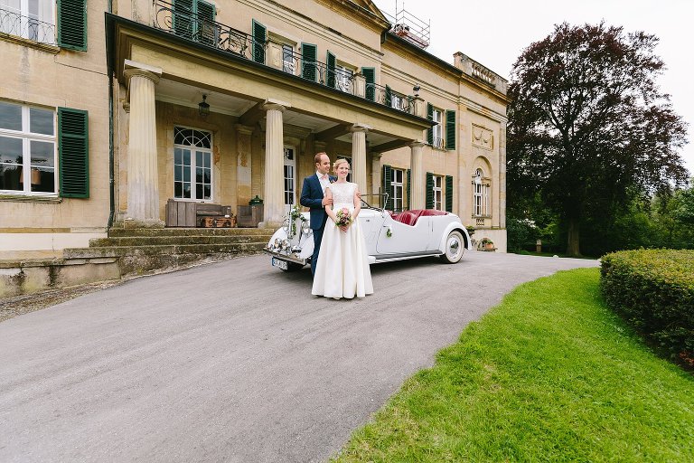 Brautpaar mit dem Auto vor dem Schloss Harkotten ©Markus Koslowski Hochzeitsfotograf Warendorf 